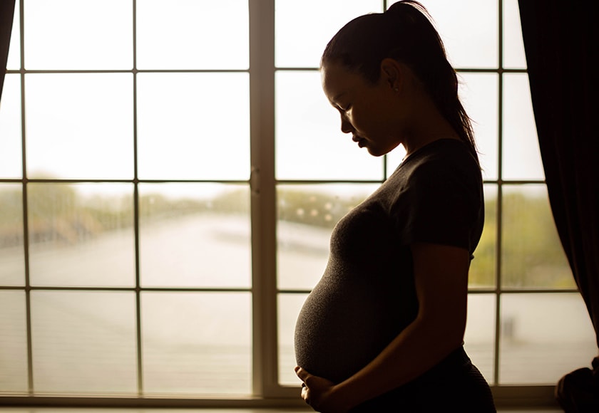 Image of pregnant woman looking pensive holding belly