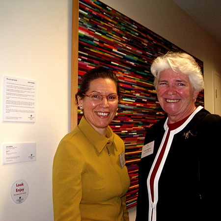 Murdoch’s first art curator Paula Silbert stands beside Sister Anne McGlinn in front of an artwork hanging on wall