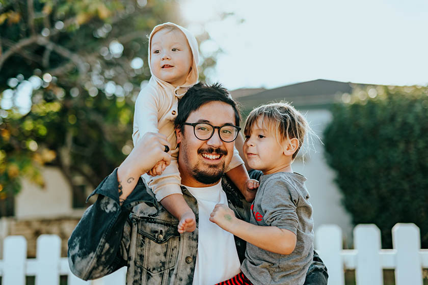 Father with toddler on his shoulders and child on his hip