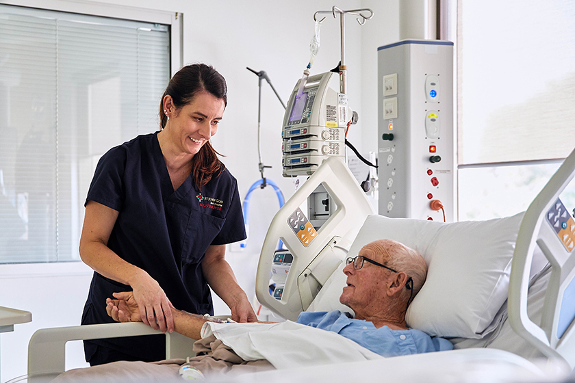 A caregiver attending to a patient in a hospital bed.