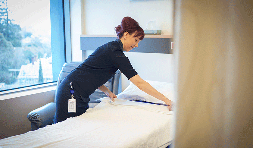 Caregiver carefully making a hospital bed