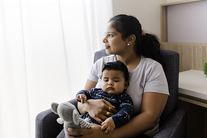 Mother sitting on armchair with infant on their lap