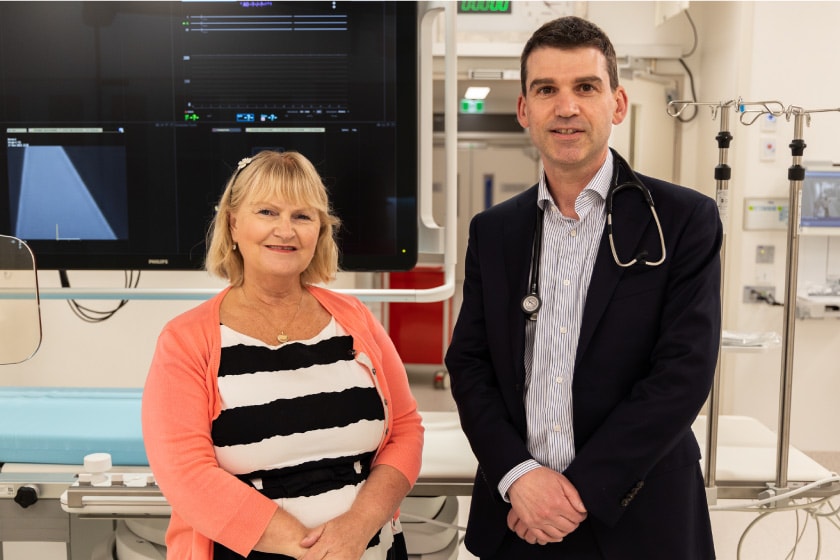 Acting CEO Maria Noonan and Cardiologist Dr Chris Hengel standing in the cath lab posing for a photo.