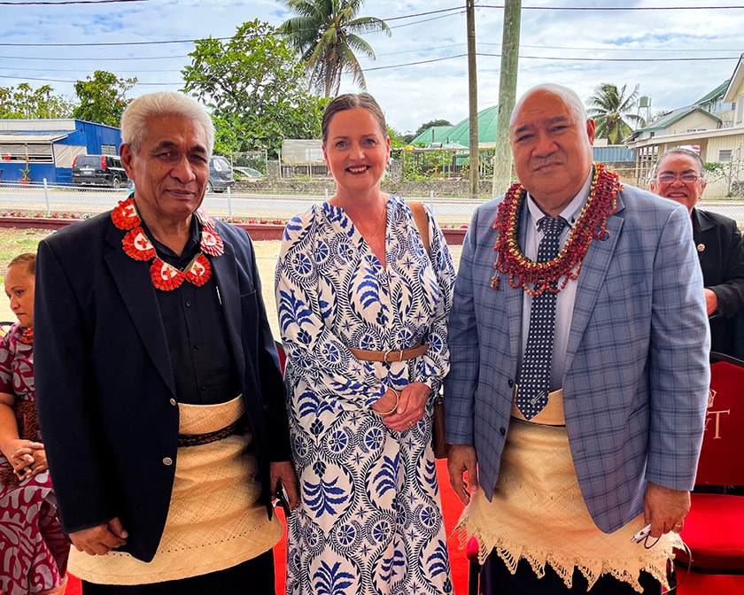 Three people standing outside looking at the camera wearing items of Tongan cultural heritage.