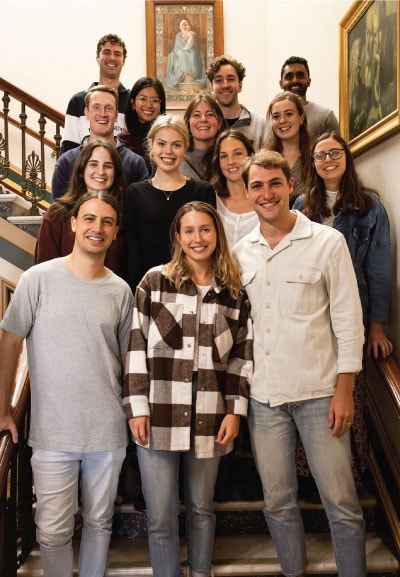 A group of 14 smiling medical students posing for a photograph