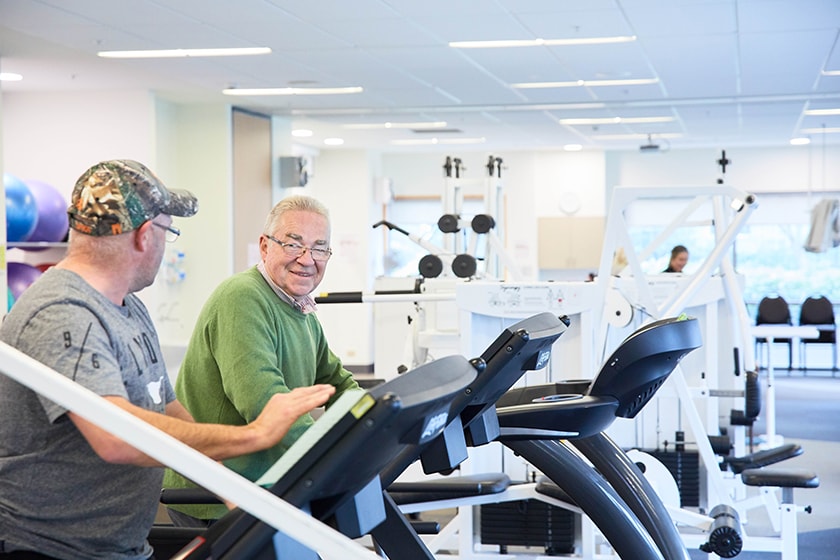 Two patients talking while using rehabilitation equipment