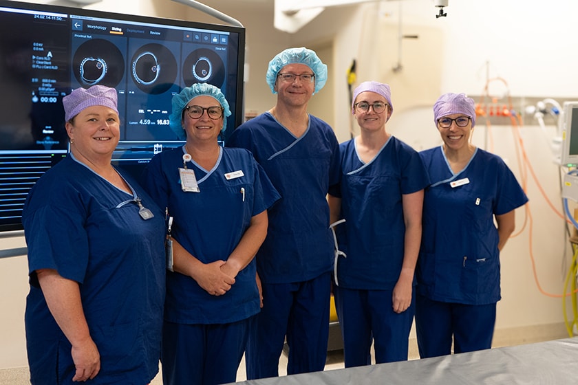 Caregivers from the St John of God Bendigo Hospital cardiac assessment unit team stand in the theatre room smiling at the camera.