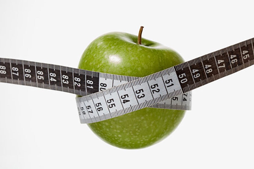 Green apple wrapped in a black and white tape measure