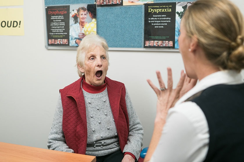 Caregiver facing patient conducting mouth exercises