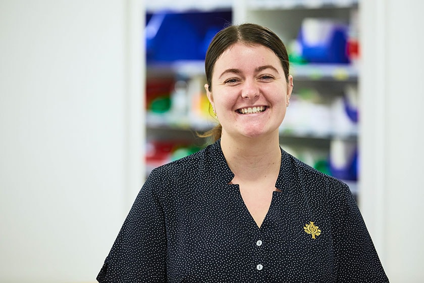 Caregiver smiling and standing in a ward setting
