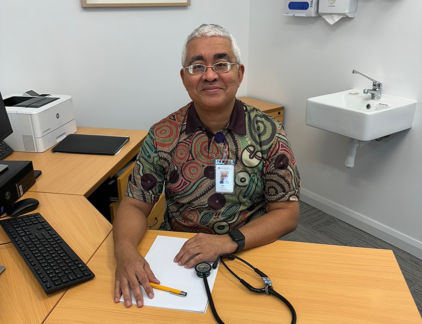 Dr Asan Akpan smiles while sitting at his desk