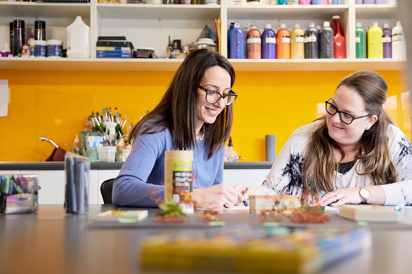 Two women sitting at table in art studio