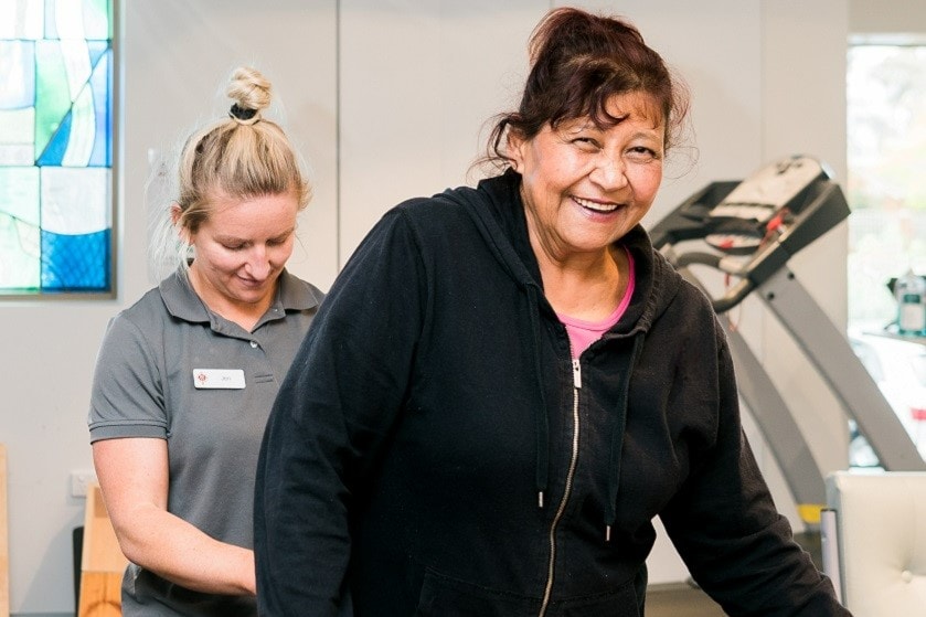 A woman undergoing rehabilitation therapy with a caregiver.