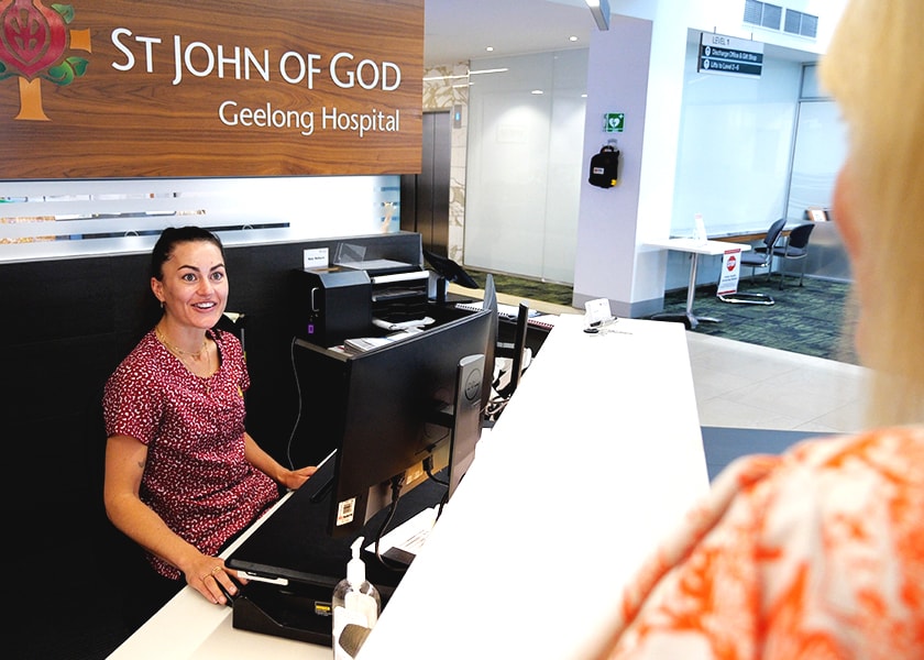 Caregiver behind reception desk greeting a visitor