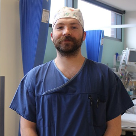 Enrolled Nurse Nicholas Harris standing in a patient room wearing scrubs at St John of God Geelong Hospital