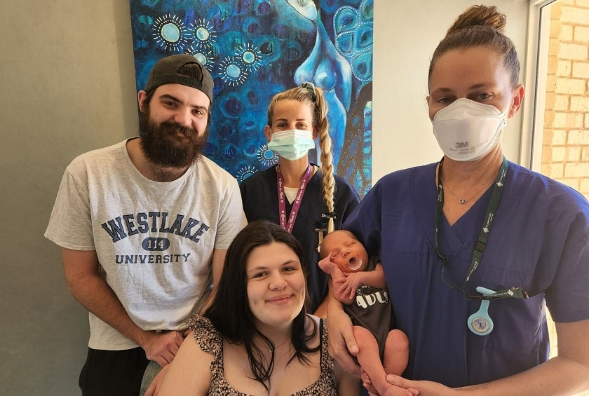 Caregivers and a family with nurse cradling a newborn baby