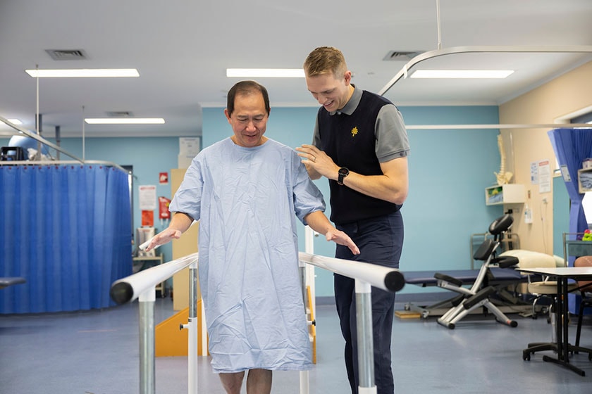A caregiver helping a patient using a rehabilitation apparatus