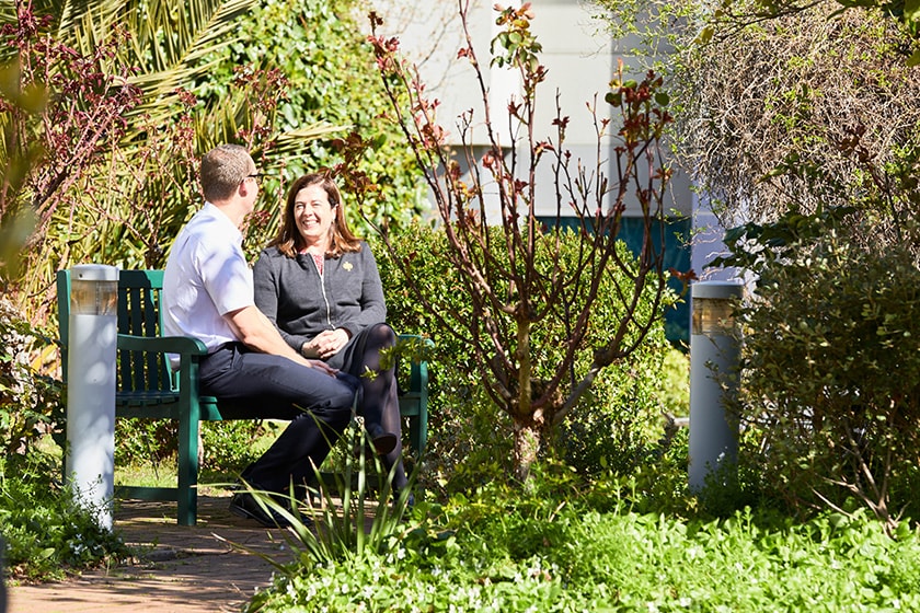 Caregiver and patient sitting on a bench in the hospital garden