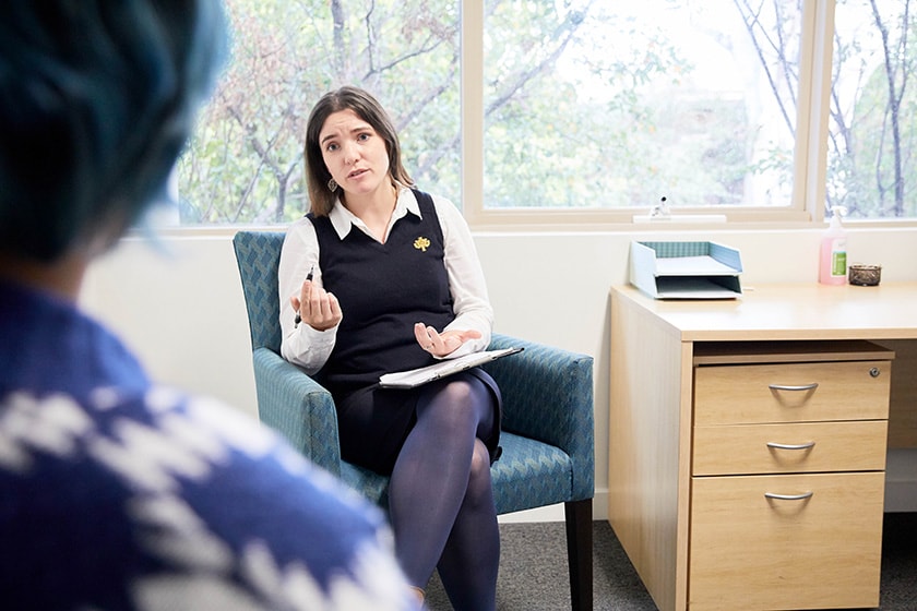 Caregiver sitting near a desk facing a patient in an office setting