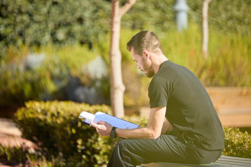 A person sitting outside reading through a paper folder.