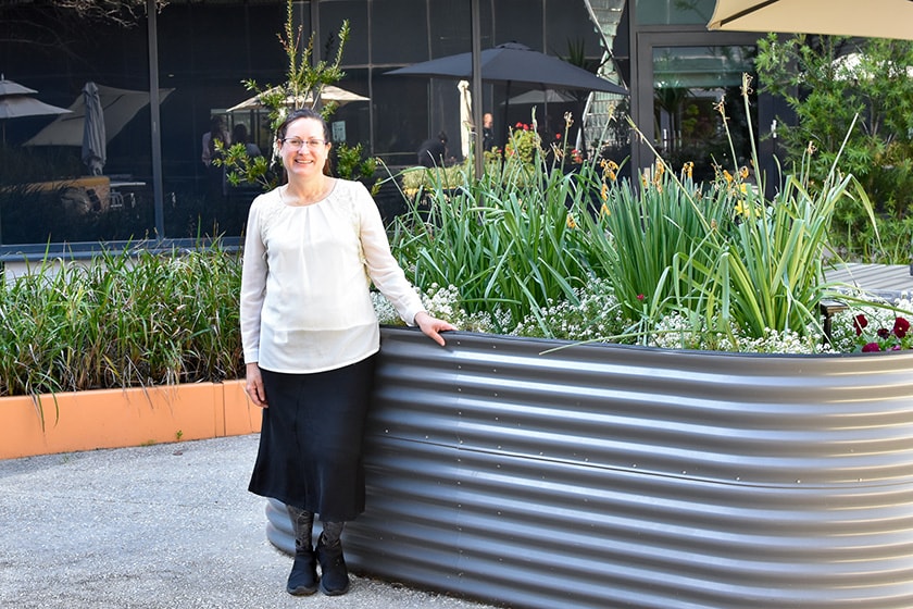 Person standing in an outdoor setting next to a plant tank