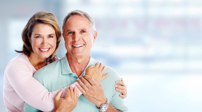Senior couple smiling as woman wraps arms around man
