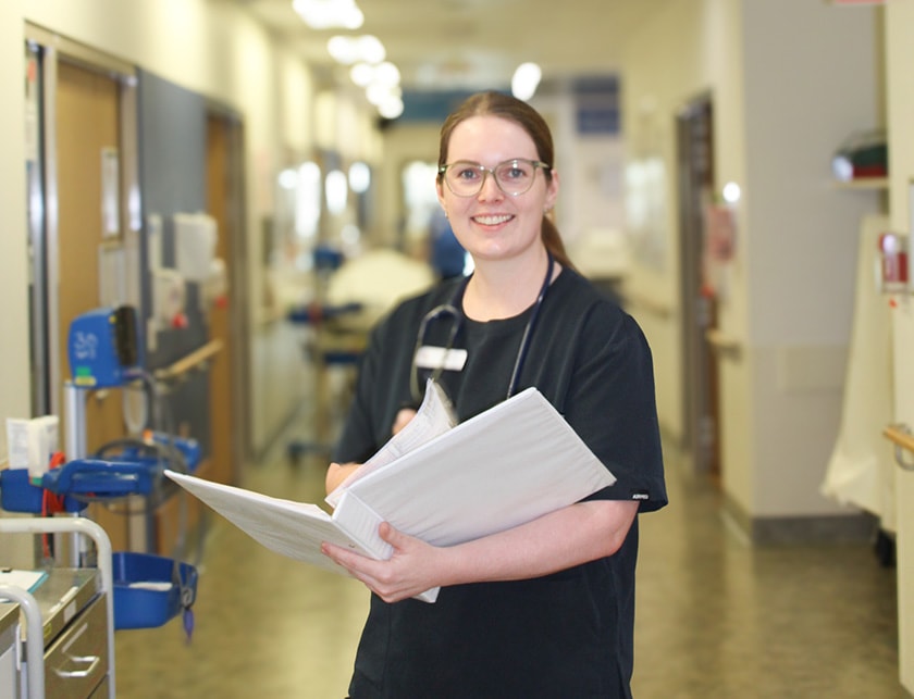 Dr Kate Hewitson smiles as she holds a folder of medical information
