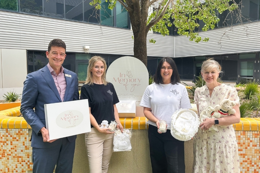 4 people are posing in front of a headstone with the engraving 