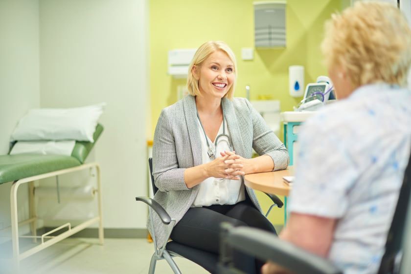 A doctor sits smiling at a patient across the table
