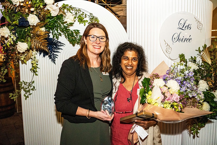Vanessa Unwin and Dr Selva Ketharanathan holding a bouquet of flowers smile for a photo.