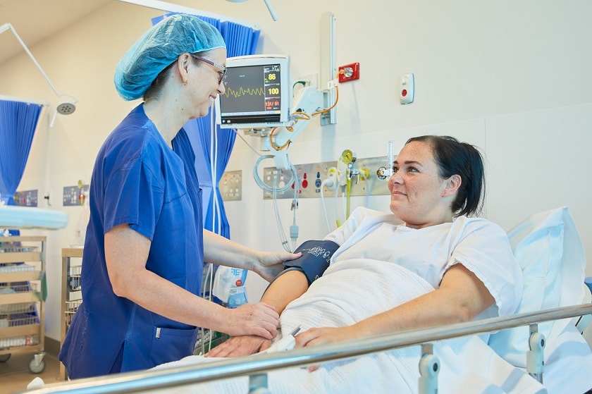 Caregiver assisting patient in hospital bed
