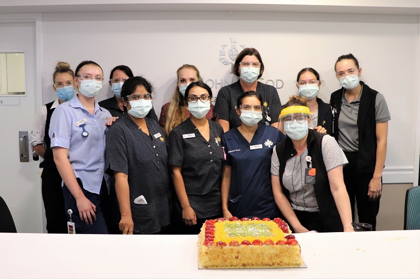 Group of nurses in PPE with a cake. 