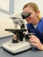 Caregiver viewing a specimen through a microscope