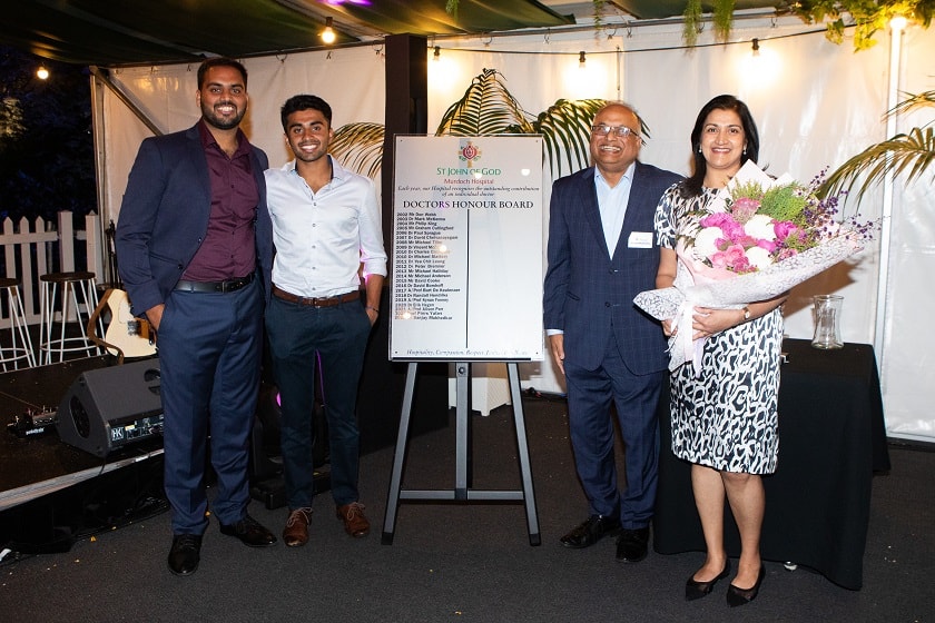 Dr Sanjay Mukhedkar with his family - his two sons are standing to the left of the picture, and Dr Mukhedkar is on the right with his wife next to him, who is holding a bouquet of flowers.
