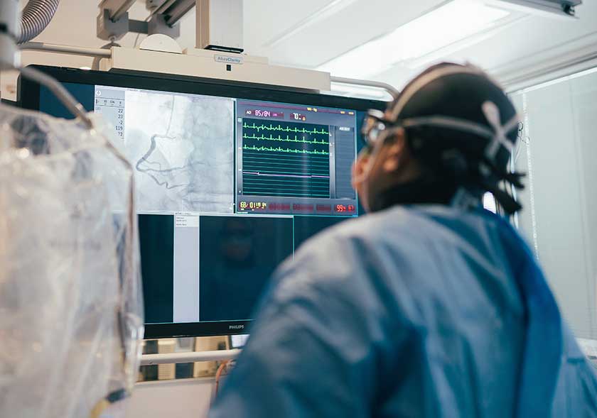Surgeon in scrubs looking at a screen during a coronary angiogram