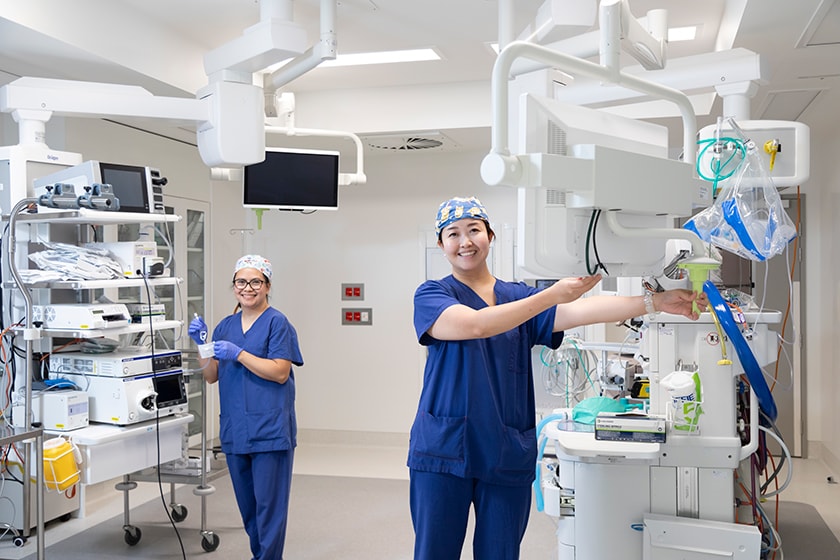 Two surgeons adjust medical imaging equipment in a theatre