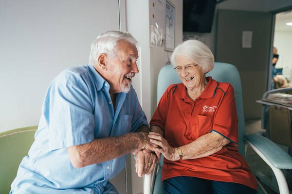 And elderly couple sits happily in the hospital while laughing together 