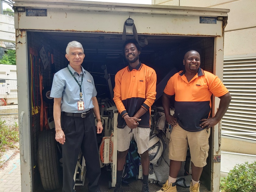 St John of God Subiaco Hospital Maintenance Planner Vivian Daniels and two people from Mama Response Kenya with a truck of donated second-hand medical equipment, smiling at the camera.