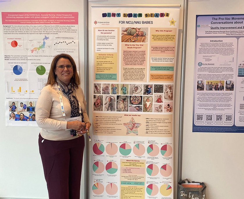 NICU Clinical Nurse Educator Christine Heald stands next to her Tiny Star Beads research poster