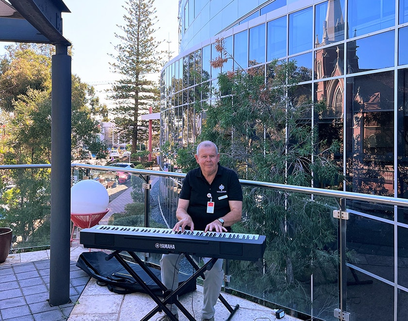 Volunteer David playing on Ward 35 balcony at St John of God Subiaco Hospital.