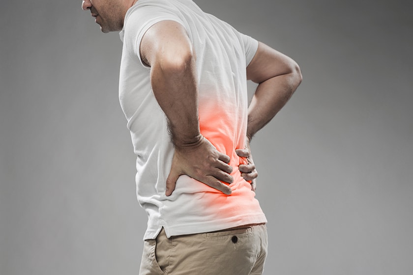 Person holding their lower back in pain, as it radiates with bright red colour.