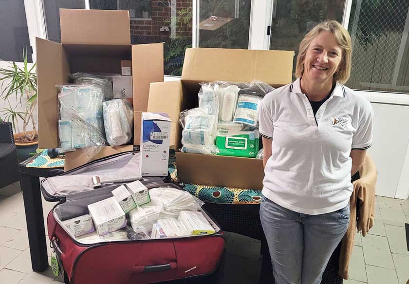 Theatre Clinical Nurse Lucy Harris smiles next to three large boxes of surgical supplies as she packs for Madagascar.