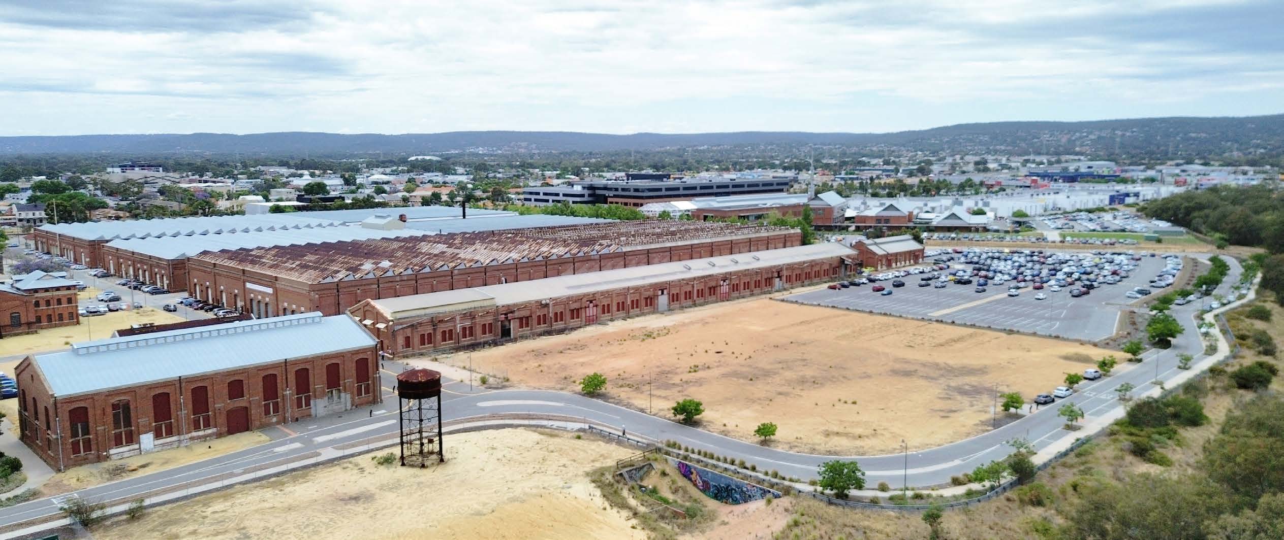 An empty block of land with buildings on one side and a road around the other, where the new St John of God Midland Private Hospital will be.