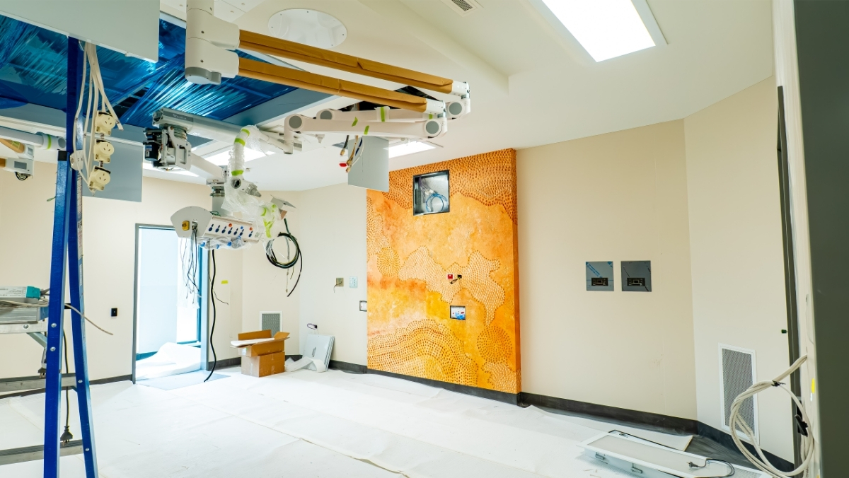 A room under construction with medical equipment and electricity cables hanging from the ceiling