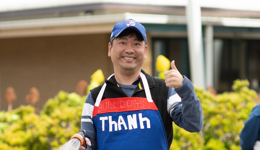 St John of God Accord disability services client wearing apron and cap giving thumbs up