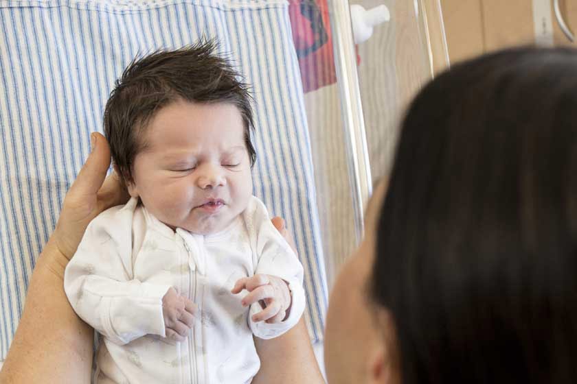 Newborn baby being held by a midwife