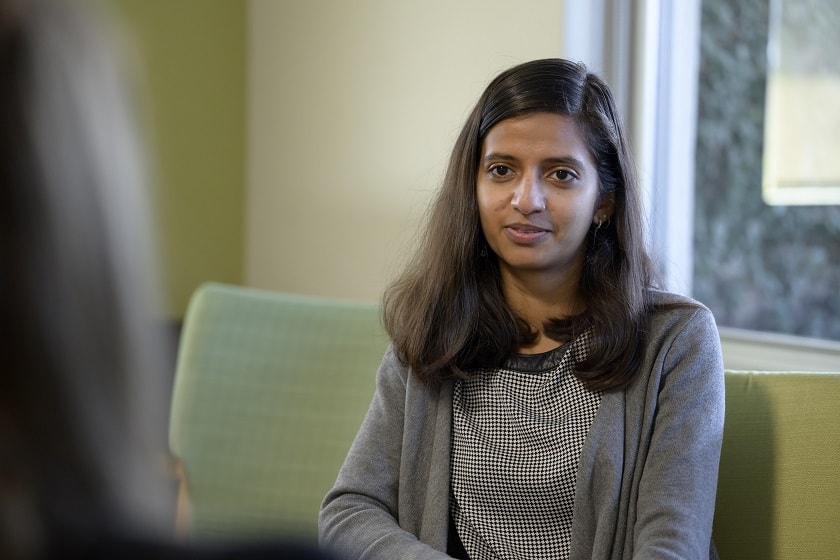 A person sits on a green chair, looking at someone off camera