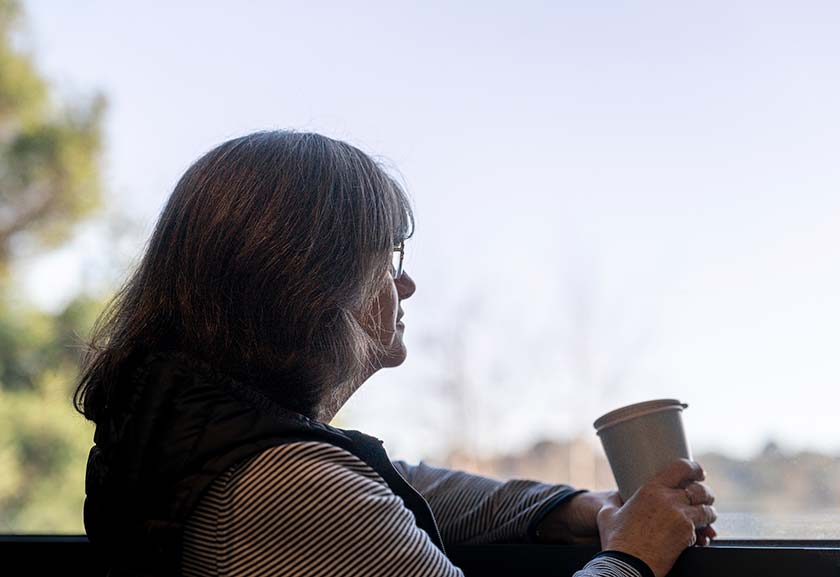 Woman looking out of a window holding a coffee cup