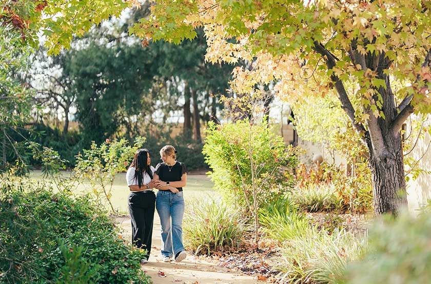 Two friends walk side-by-side out in nature