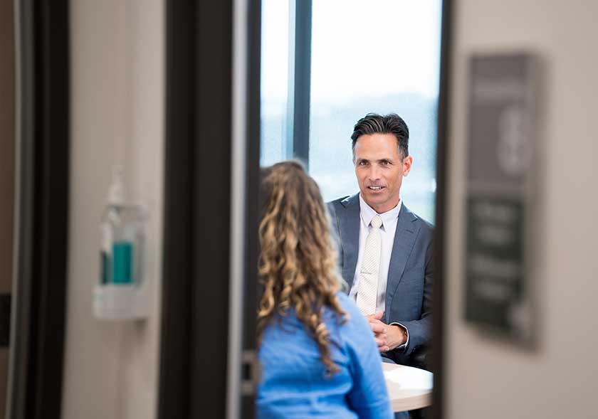 Specialist sits listening to patient across from him
